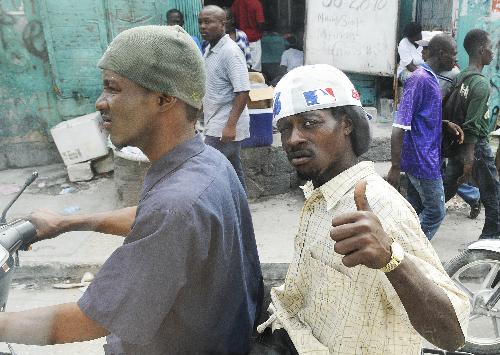 A man gestures as he rides on a motorcycle past a temporary hospital in Haitian capital Port-au-Prince, on January 26, 2010, the 15th day after the catastrophic earthquake. 