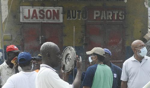 A man holds a gear in front of a shop selling car accessories in the street in Port-au-Prince, capital of Haiti, January 26, 2010. 