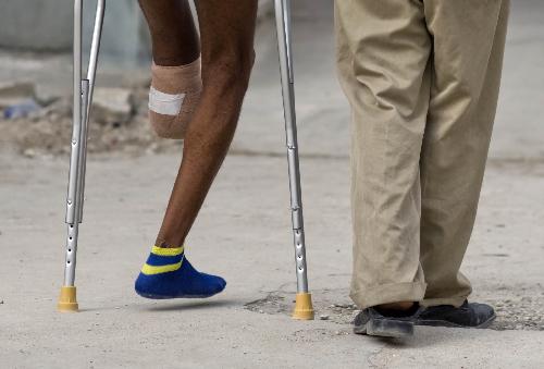 A man injured in the earthquake walks with a family member after the amputation in a hospital in Port-au-Prince, capital of Haiti, January 26, 2010. 
