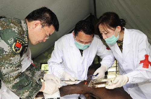 Wang Yurong (1st L), head of a Chinese medical team, works with two other team members on the wound of an injured man at a makeshift hospital that the team has set up in Port-au-Prince January 27, 2010. 
