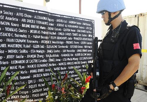 A Chinese peacekeeping policeman looks at the names of UN staff members dead in the earthquake during a memorial service in Port-au-Prince, capital of Haiti, January 28, 2010. The UN confirmed on Thursday that 85 of it staff members lost their lives in the earthquake. 