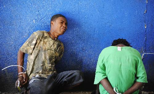 Looters wait to be interrogated at a police office in Port-au-Prince, capital of Haiti, January 29, 2010. More than 50 people looted an electrical appliance shop here on Friday. US soldiers and Haiti policemen detained the looters after a cross fire, with one looter shot dead.