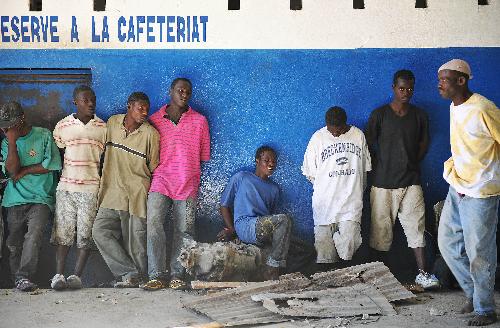 Looters wait to be interrogated at a police office in Port-au-Prince, capital of Haiti, January 29, 2010. More than 50 people looted an electrical appliance shop here on Friday. US soldiers and Haiti policemen detained the looters after a cross fire, with one looter shot dead.