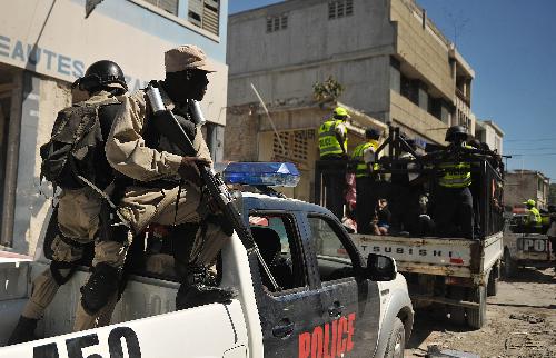 Policemen escort looters to a police office in Port-au-Prince, capital of Haiti, on January 29, 2010. More than 50 people looted an electrical appliance shop here on Friday. US soldiers and Haiti policemen detained the looters after a cross fire, with one looter shot dead. 