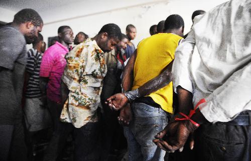 Looters are sent to a police office in Port-au-Prince, capital of Haiti, on January 29, 2010. More than 50 people looted an electrical appliance shop here on Friday. US soldiers and Haiti policemen detained the looters after a cross fire, with one looter shot dead.