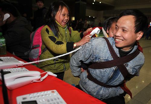 Lu Laofa (R), a 40-year-old migrant worker from southwest China's Guizhou Province, and his children make a free phone call with their relatives at the railway station of Hangzhou, capital of east China's Zhejiang Province, January 31, 2010. The railway station provides free phone call service for migrant workers during the Spring Festival travel peak. Some 20 million migrant workers in Zhejiang Province began to return home for Spring Festival which falls on February 14 this year.