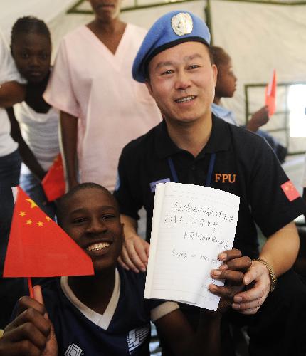 Hu Yunwang (R Front), political commissar of the Chinese anti-riot police team in Haiti, displays his greetings to Haitian orphans with a boy at the orphanage 'solidarity and fraternity' in Port-au-Princes, capital of Haiti, January 30, 2010.