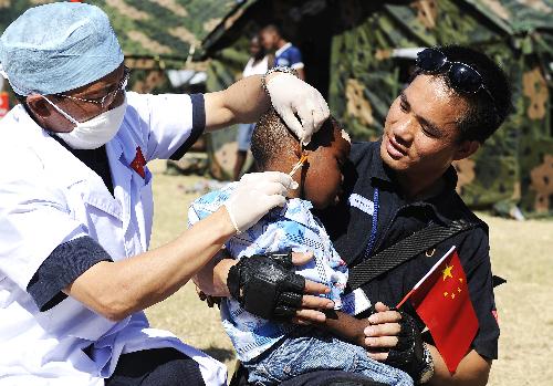 A member of the Chinese anti-riot police team in Haiti holds an orphan in his arms as a doctor cleans his wounds at the orphanage 'solidarity and fraternity' in Port-au-Princes, capital of Haiti, January 30, 2010.