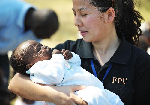 A member of the Chinese anti-riot police team in Haiti holds a four-month-old orphan in her arms at the orphanage 'solidarity and fraternity' in Port-au-Princes, capital of Haiti, January 30, 2010. 