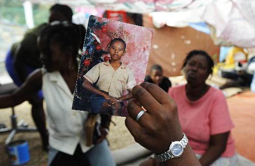 A woman shows her picture at a young age at a temporary settlement for quake victims outside the presidential palace in Port-au-Princes, capital of Haiti, January 31, 2010. 
