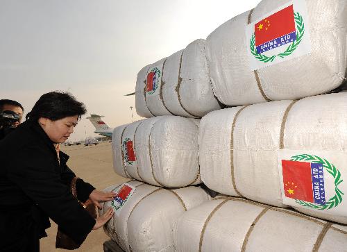 A Chinese official sticks signs of 'China Aid' on bags of emergency aid materials at Zhengding International Airport in Shijiazhuang, capital of north China's Hebei Province, January 31, 2010. Three military transport planes carrying some emergency aid materials flew to Mongolia on Sunday. 