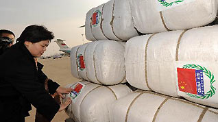 A Chinese official sticks signs of 'China Aid' on bags of emergency aid materials at Zhengding International Airport in Shijiazhuang, capital of north China's Hebei Province, January 31, 2010. Three military transport planes carrying some emergency aid materials flew to Mongolia on Sunday.