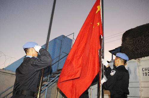 Chinese peacekeeping police officers raise China's national flag during a ceremony in memory of the eight Chinese peacekeeping police officers dead in the recent quake in Haiti, at the encampment of the Chinese peacekeeping anti-riot police team in Port-au-Prince, capital of Haiti, February 1, 2010. 