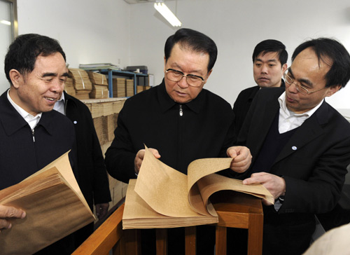 Li Changchun (C), member of the Standing Committee of the Political Bureau of the Central Committee of the Communist Party of China(CPC), looks at a braille book during his visit to the China Braille Publishing House in Beijing, capital of China, February 2, 2010.