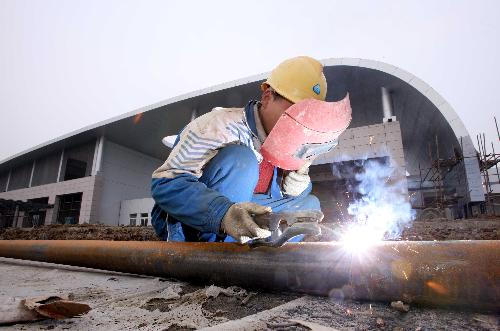 A worker welds a pipe at the construction site of the passenger center in Mianzhu City, southwest China's Sichuan Province, January 30, 2010. 