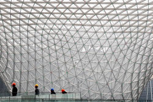 Workers walk past the Sun Valley of the Expo Axis equipped with LED lights in the 2010 World Expo Site in east China's Shanghai Municipality, February 3, 2010.