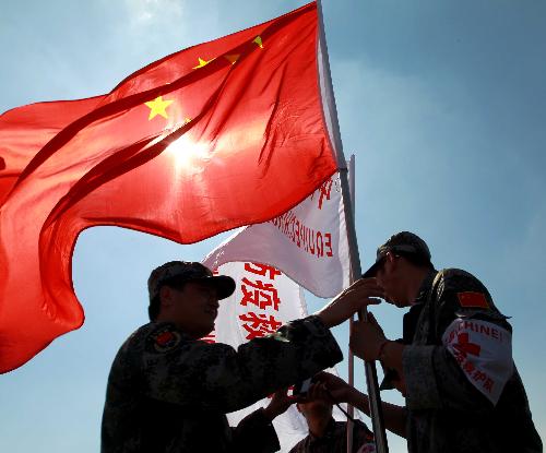 A member of the Chinese medical team (R) hands over the national flag to a member of the Chinese anti-riot team in Haiti at the international airport in Port-au-Prince, capital of Haiti, February 8, 2010.