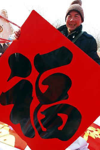 A citizen shows a well-wishing decoration with Chinese character 'fu', meaning 'fortune', at Zhoucun Village of Zibo, east China's Shandong Province, Feb. 12, 2010. Various kinds of well-wishing decorations were on hot sale with the Chinese traditional lunar Year of the Tiger draws near. 