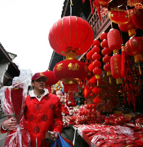 A young man in 'Tangzhuang', a kind of traditional Chinese costume, buys Spring Festival decorations in Zhoushan, east China's Zhejiang Province, Feb. 12, 2010.