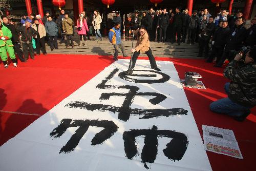 Calligrapher Mei Aoxue writes a large Chinese character 'chun', meaning 'spring', during a cultural temple fair in Jinan, capital of east China's Shandong Province, Feb. 13, 2010. The 15th Minghu Lake Spring Festival Cultural Temple Fair was opened in Jinan on Saturday.