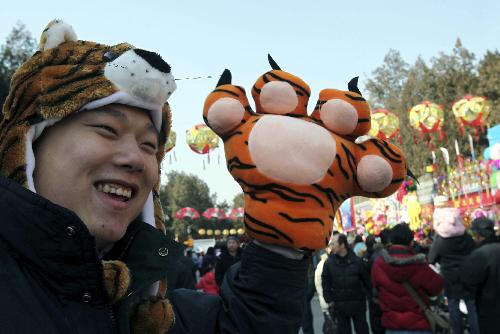 A young man in 'tiger' cap and glove visits the Ditan temple fair in Beijing, capital of China, Feb. 13, 2010. Tiger-themed toys become popular at Spring Festival temple fair. 