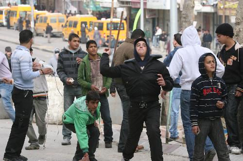 Palestinians throw stones at an Israeli army vehicle during a demonstration in the West Bank city of Hebron, on Feb. 22, 2010. 