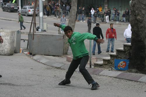 A Palestinian youth throws stones at an Israeli army vehicle during a demonstration in the West Bank city of Hebron, on Feb. 22, 2010. 