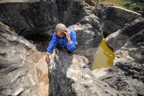 An elder peasant squats beside a disappearing pond due to severe drought in the Bouyei and Miao autonomous prefecture, southwest China's Guizhou province, February 23, 2010.
