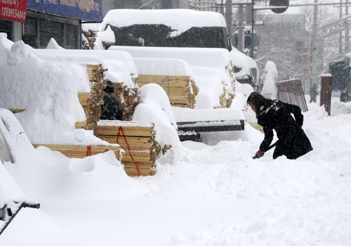 A woman clears snow on the road in Kuitun City, northwest China's Xinjiang Uygur Autonomous Region, Feb. 23, 2010. 