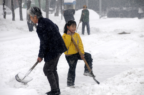 People clear snow on the road in Kuitun City, northwest China's Xinjiang Uygur Autonomous Region, Feb. 23, 2010.