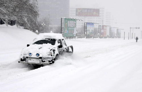A car covered with snow moves on the road in Kuitun City, northwest China's Xinjiang Uygur Autonomous Region, Feb. 23, 2010. 