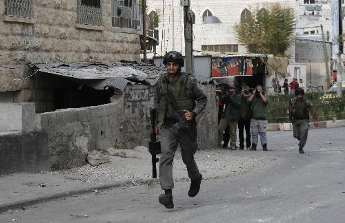 An Israeli soldier runs to take position during clashes in the West Bank city of Hebron, Feb. 24, 2010. 