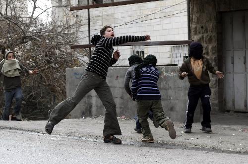 Palestinian protesters throw stones towards Israeli soldiers during clashes in the West Bank city of Hebron, Feb. 24, 2010.