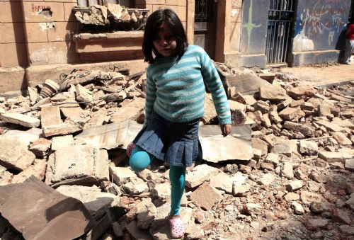 A Chilean girl walks past a destroyed building in Santiago, Chile, Feb. 28, 2009.