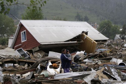 A woman holding a child stands among debris in earthquake-and-tsunami-devastated Dichato town, some 30 kilometers north of Concepcion, Chile, March 1, 2010. 