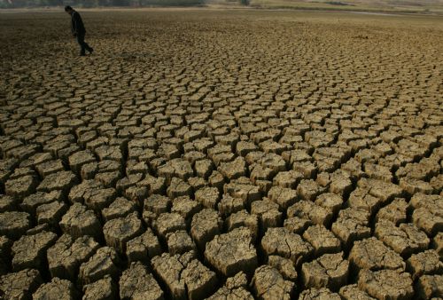 A man walks on a dried-up reservoir in Caoba Town of Mengzi County, southwest China's Yunnan province, March 1, 2010. Continual drought has hit the county of Honghe Hani and Yi Autonomous Prefecture, since September 2009, resulting in serious water shortage. 