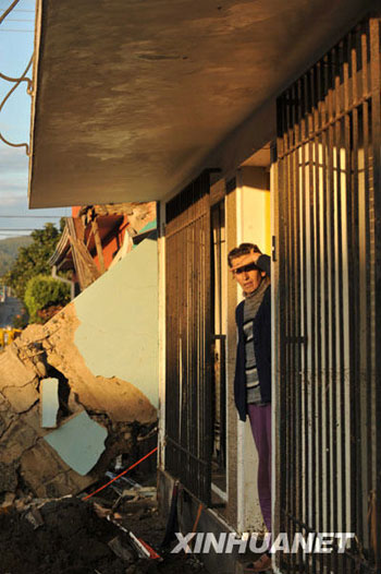 A woman looks out from the doorway of her house in Constitución, a town 450 km south of Chilean capital Santiago on March 2, 2010.