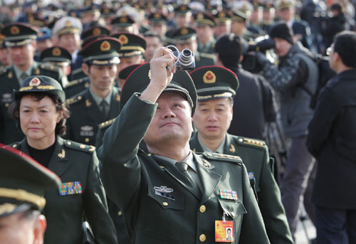 A deputy (front) to the Third Session of the 11th National People&apos;s Congress (NPC) takes pictures while walking to the Great Hall of the People in Beijing, capital of China, March 5, 2010. 