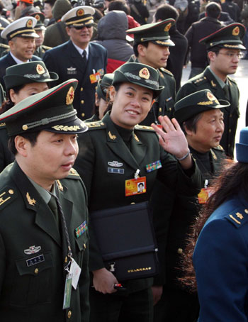 A female deputy (C) to the Third Session of the 11th National People&apos;s Congress (NPC) gestures to camera while walking to the Great Hall of the People in Beijing, capital of China, March 5, 2010. 