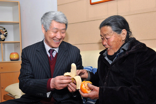 Zhao Zhiquan, a deputy to the NPC and chairman of a pharmaceutical firm in east China's Shandong province, peels a banana for an older woman, March 2, 2010. 