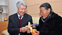 Zhao Zhiquan, a deputy to the NPC and chairman of a pharmaceutical firm in east China's Shandong province, peels a banana for an older woman, March 2, 2010.