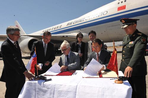 Chinese Ambassador to Chile Lu Fan (2nd R) and a Chilian official (3rd R) sign on the documents about the aid goods at the airport in Santiago, capital of Chile, March 5, 2010. A Chinese plane carrying US$2 million worth of aid goods arrived.