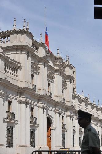 People walk past flags flying at half mast at the presidential palace in Santiago, capital of Chile, March 7, 2010. 