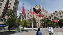 People walk past flags flying at half mast at the presidential palace in Santiago, capital of Chile, March 7, 2010.