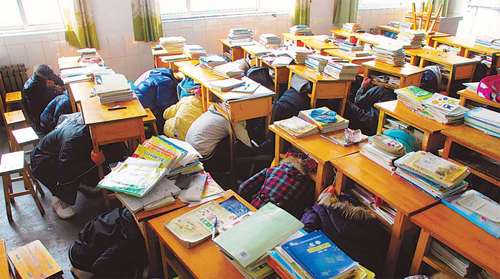 Students at the Experimental High School in Zouping County, Shandong Province, take cover under their desks during an earthquake drill on Tuesday.