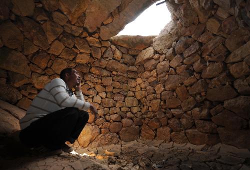 A villager sits beside a drid well in water cellar in Huize County of Qujing City, southwest China's Yunnan Province, on March 7, 2010.