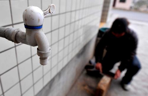 Photo taken on March 9, 2010 shows Zhang Min, a villager in Ketuo Village, works beside a water-tap without running water, in Puding County, southwest China's Guizhou Province, March 9, 2010. 