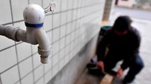 Photo taken on March 9, 2010 shows Zhang Min, a villager in Ketuo Village, works beside a water-tap without running water, in Puding County, southwest China's Guizhou Province, March 9, 2010.