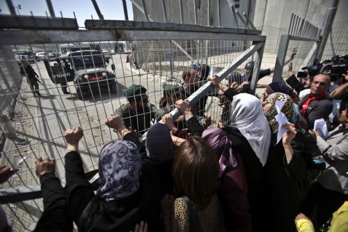 Palestinian demonstrators try to break through an Israeli checkpoint gate during a demonstration against Israeli closure in Qalandiya checkpoint near Jerusalem City on March 13, 2010.