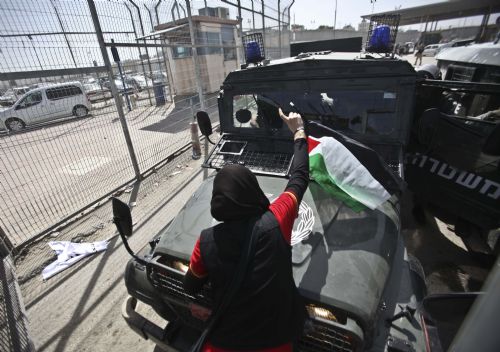 A Palestinian girl places a flag on an Israeli military jeep during a demonstration against Israeli closure in Qalandiya checkpoint near Jerusalem City on March 13, 2010. 